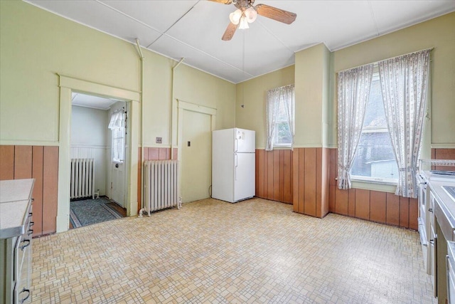 empty room featuring radiator, a wainscoted wall, and ceiling fan