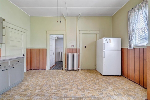 kitchen with radiator, a wainscoted wall, and freestanding refrigerator