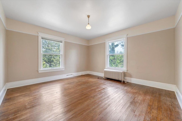 spare room with radiator heating unit, a wealth of natural light, hardwood / wood-style floors, and baseboards