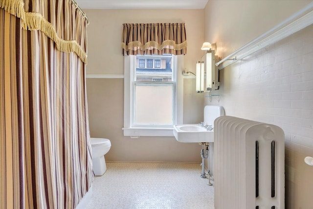 bathroom with radiator, toilet, and baseboards
