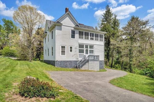 rear view of property featuring a chimney, stairway, and a yard