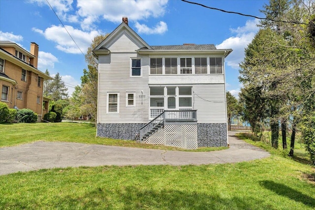 rear view of house featuring stairway and a yard