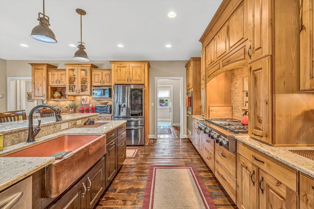 kitchen featuring light stone countertops, a sink, appliances with stainless steel finishes, and tasteful backsplash