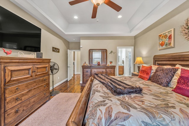 bedroom with a tray ceiling, wood finished floors, baseboards, and recessed lighting