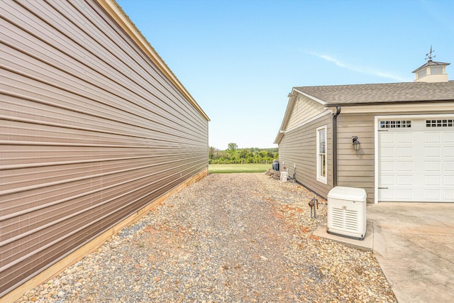 view of side of property featuring a shingled roof and a garage