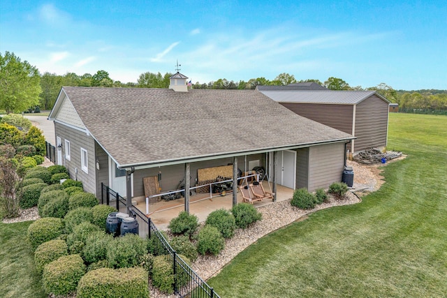 back of property featuring a patio area, a yard, and a shingled roof