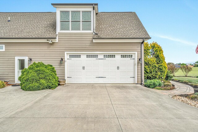 view of side of property featuring driveway and a shingled roof