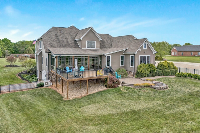 back of property featuring a lawn, a fire pit, a fenced backyard, a wooden deck, and roof with shingles