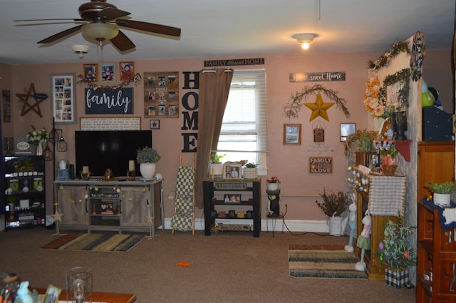 living area featuring a ceiling fan, baseboards, and carpet floors