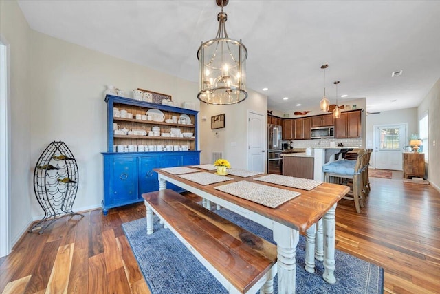 dining room with wood finished floors, a chandelier, baseboards, and recessed lighting
