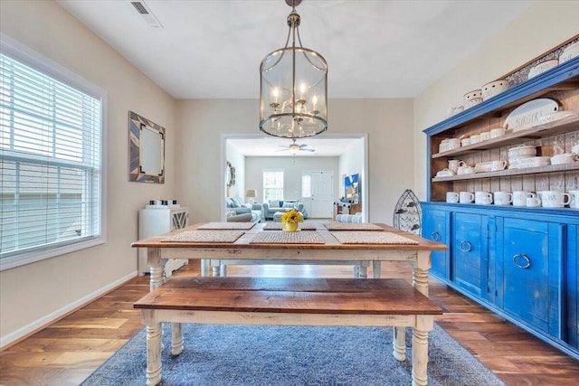 dining space with a chandelier, wood finished floors, baseboards, and ceiling fan