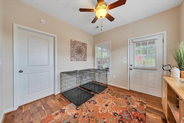 doorway with wood finished floors, ceiling fan, and baseboards