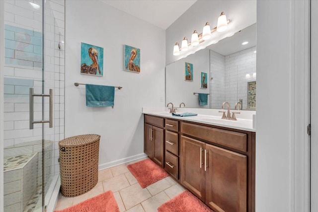 bathroom with tiled shower, tile patterned floors, double vanity, and baseboards