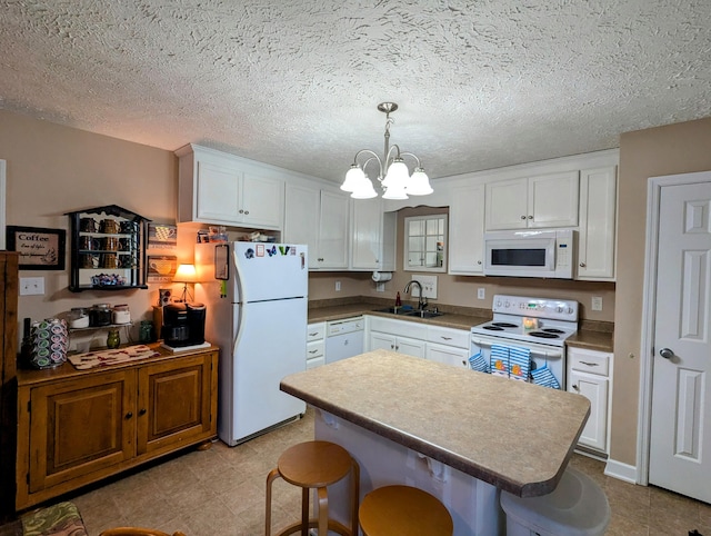 kitchen featuring white cabinets, an inviting chandelier, a sink, and white appliances