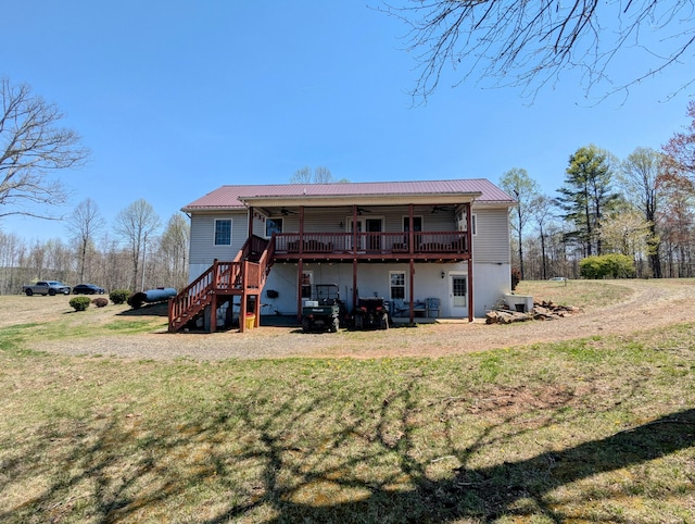 rear view of property with a lawn, a ceiling fan, stairs, and metal roof