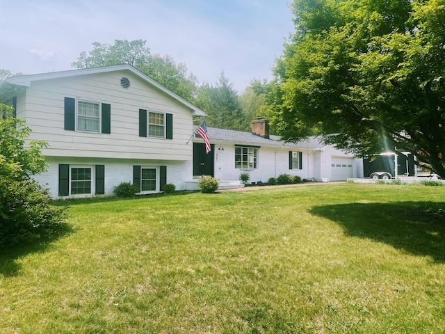 tri-level home featuring an attached garage, a chimney, and a front yard