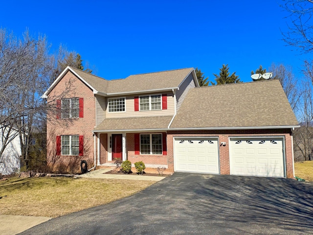 traditional-style home with aphalt driveway, covered porch, brick siding, a front yard, and a garage
