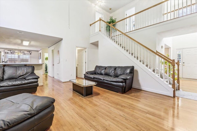 living room featuring baseboards, a towering ceiling, stairs, and wood-type flooring