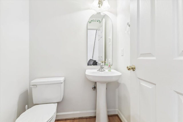 bathroom with a sink, toilet, wood finished floors, and baseboards