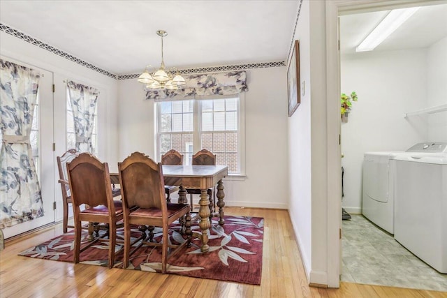 dining space featuring separate washer and dryer, baseboards, a chandelier, and light wood-style flooring