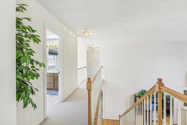 hall featuring baseboards, carpet floors, and an upstairs landing