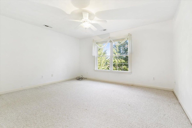 empty room with carpet floors, visible vents, and ceiling fan
