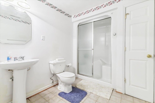 full bath with tile patterned floors, toilet, a sink, baseboards, and a stall shower