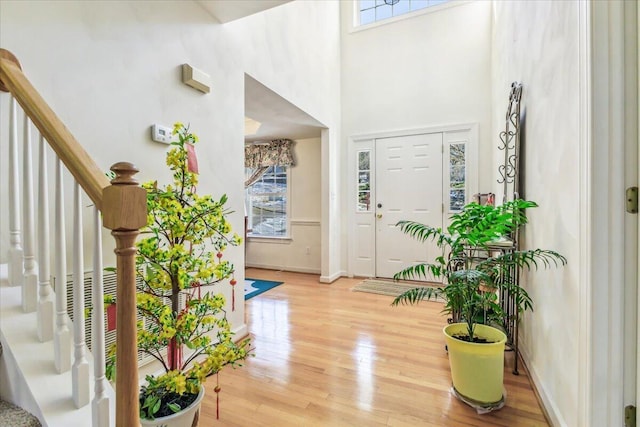 foyer entrance featuring stairway, baseboards, a healthy amount of sunlight, and light wood-type flooring