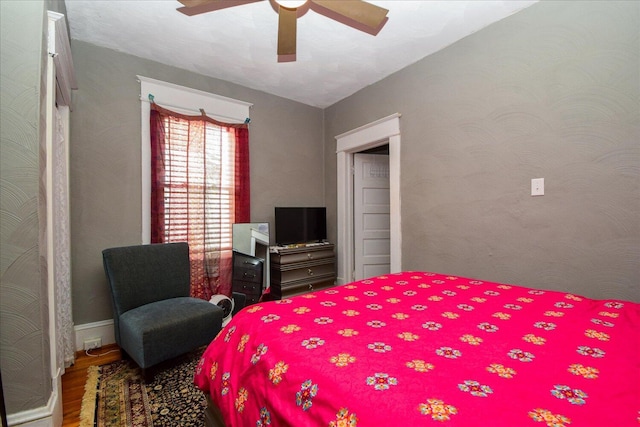 bedroom featuring wood finished floors, baseboards, and ceiling fan