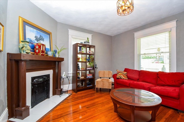 living area featuring a fireplace with flush hearth, baseboards, wood finished floors, and plenty of natural light