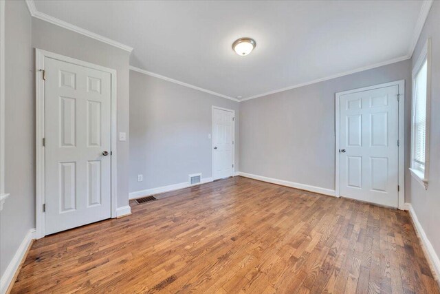 unfurnished bedroom with visible vents, baseboards, and wood finished floors
