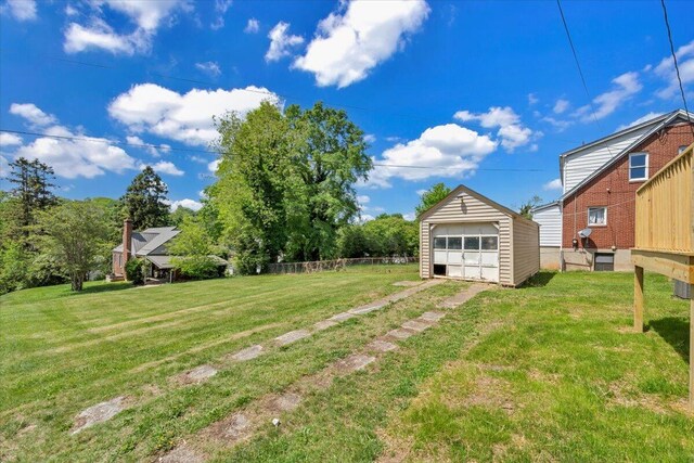 view of yard featuring fence, driveway, an outbuilding, and a garage