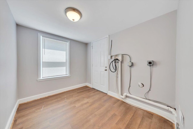 interior space with light wood-style flooring, hookup for a washing machine, baseboards, and laundry area