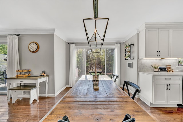 dining area featuring baseboards, a chandelier, ornamental molding, and wood finished floors