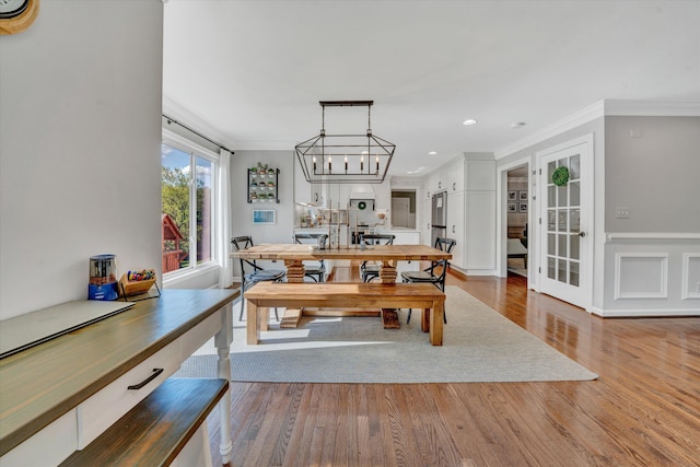 dining space with an inviting chandelier, french doors, recessed lighting, wood finished floors, and ornamental molding