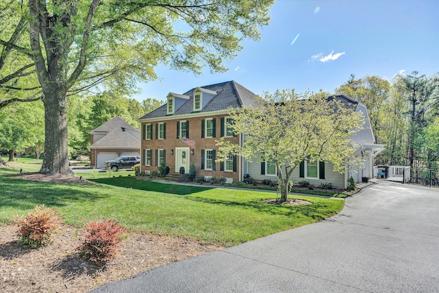 view of front of home featuring brick siding, a garage, a front yard, and aphalt driveway