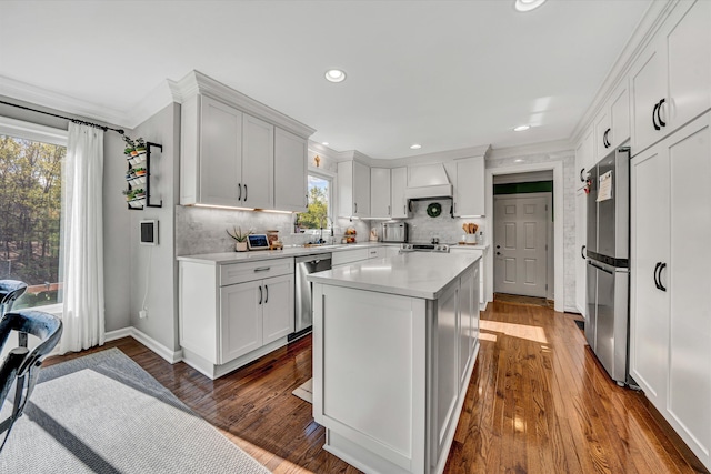 kitchen with light countertops, a center island, stainless steel appliances, baseboards, and tasteful backsplash