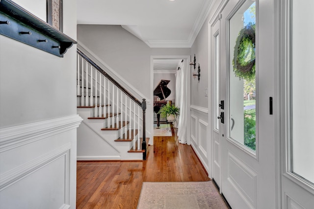 entrance foyer with crown molding, plenty of natural light, stairway, and wood finished floors