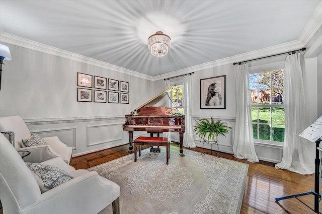 living area featuring crown molding, a decorative wall, hardwood / wood-style flooring, and a chandelier