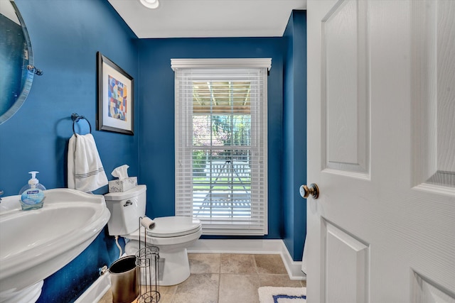 half bath with toilet, baseboards, and a sink