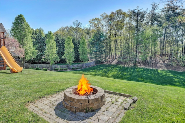 view of yard featuring a playground, fence private yard, a fire pit, and a patio