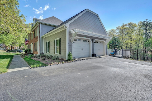 view of property exterior featuring an attached garage, fence, and driveway