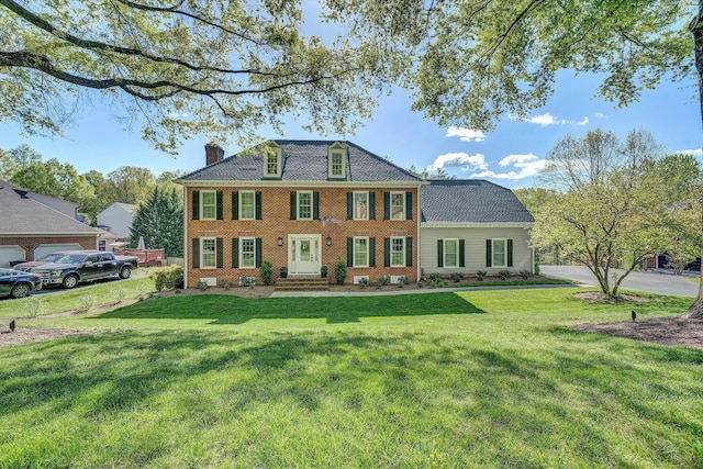 view of front of home featuring brick siding, a front yard, and a chimney