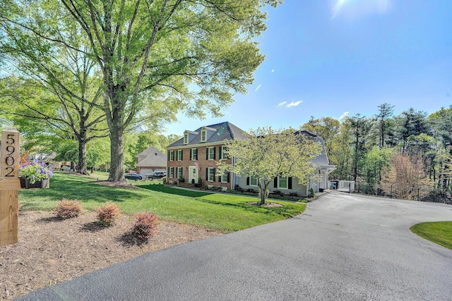 view of front of property with brick siding, fence, driveway, and a front yard