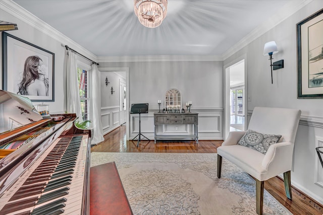 living area with crown molding, a decorative wall, wood finished floors, and a wealth of natural light