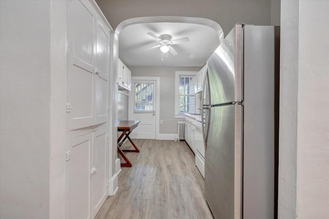 hallway with a sink, baseboards, and light wood-type flooring