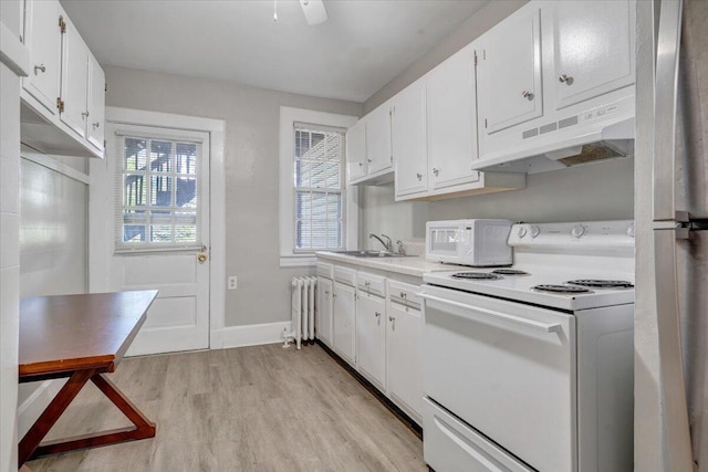 kitchen featuring white cabinetry, white appliances, under cabinet range hood, light countertops, and radiator heating unit
