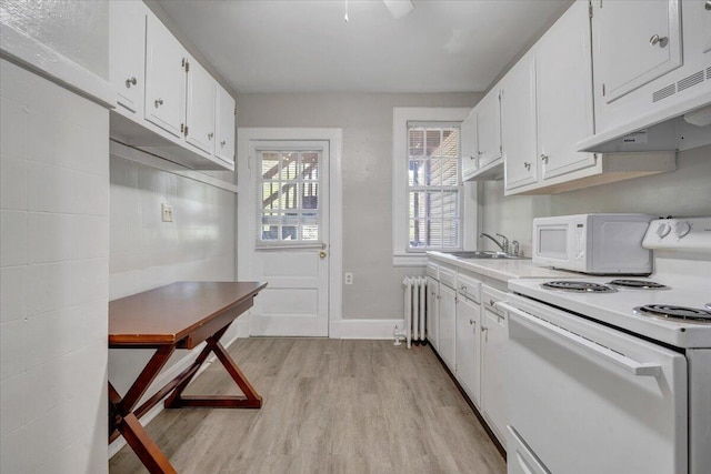 kitchen with light wood-style flooring, under cabinet range hood, white appliances, radiator heating unit, and a sink