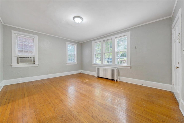 spare room with light wood-type flooring, radiator, baseboards, and crown molding