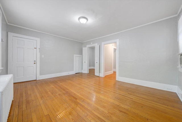 unfurnished living room featuring light wood finished floors, crown molding, and baseboards